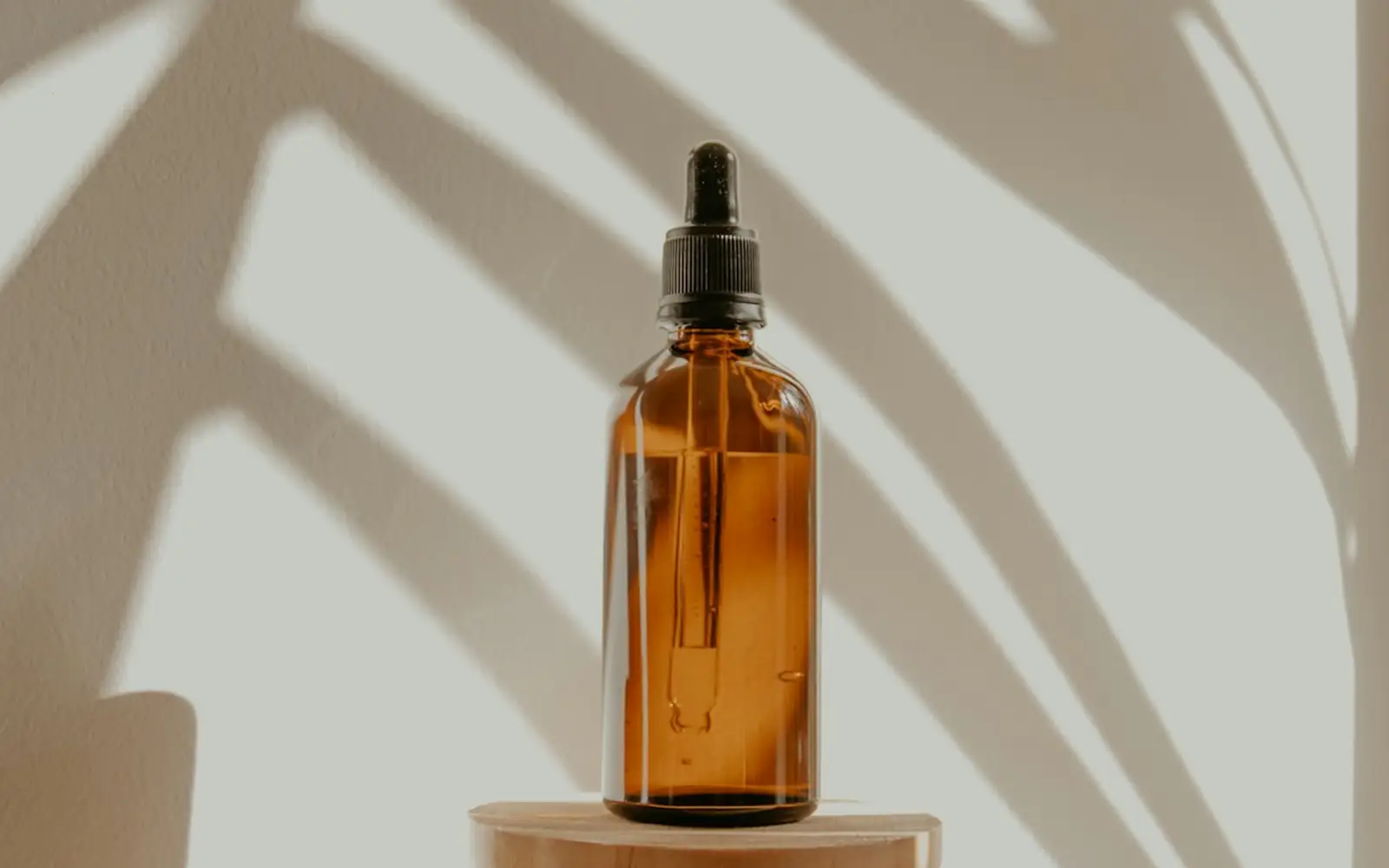 An amber dropper bottle on a wooden stand