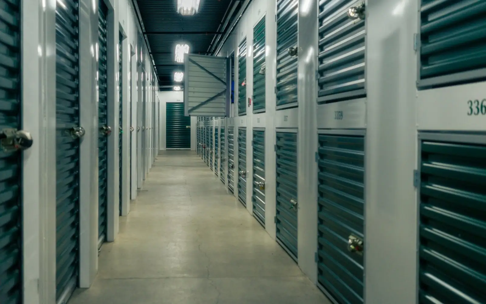 A corridor of green storage unit doors